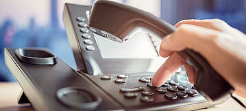 Eine Person wählt eine Nummer am Telefon