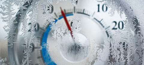 Thermometer hinter Glas. Frost auf dem Fenster im Fokus.