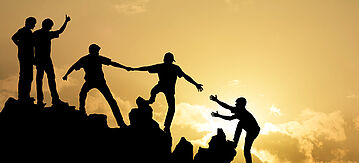 Silhouetten einer Gruppe von Menschen beim Bergsteigen